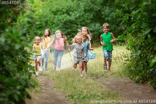 Image of Kids, children running on green meadow, forest. Childhood and summertime