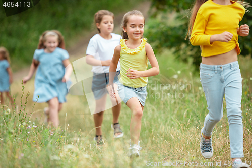 Image of Kids, children running on green meadow, forest. Childhood and summertime