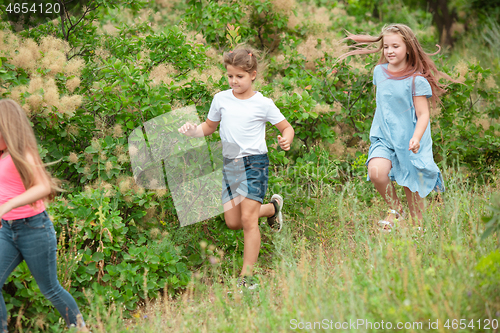 Image of Kids, children running on green meadow, forest. Childhood and summertime