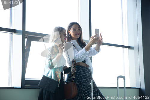 Image of Young women waiting for departure in airport, traveler with small baggage, influencer\'s lifestyle