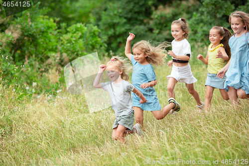 Image of Kids, children running on green meadow, forest. Childhood and summertime