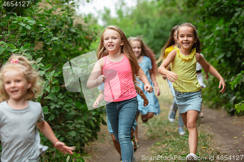 Image of Kids, children running on green meadow, forest. Childhood and summertime