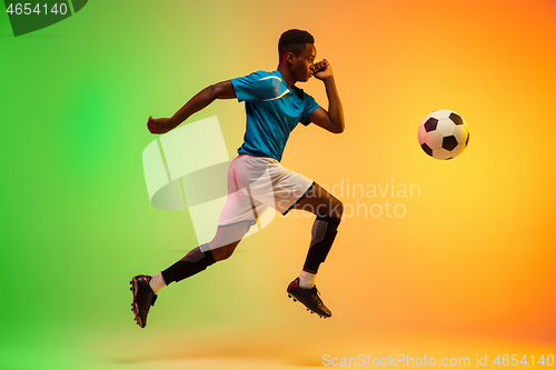 Image of Male soccer, football player training in action isolated on gradient studio background in neon light