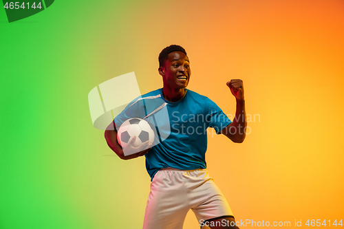 Image of Male soccer, football player training in action isolated on gradient studio background in neon light