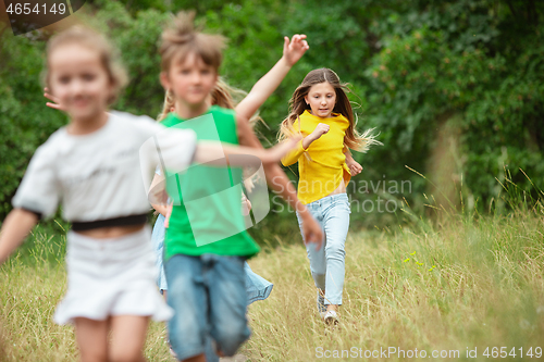 Image of Kids, children running on green meadow, forest. Childhood and summertime