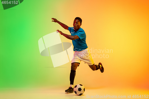 Image of Male soccer, football player training in action isolated on gradient studio background in neon light