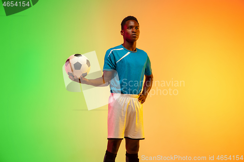 Image of Male soccer, football player training in action isolated on gradient studio background in neon light