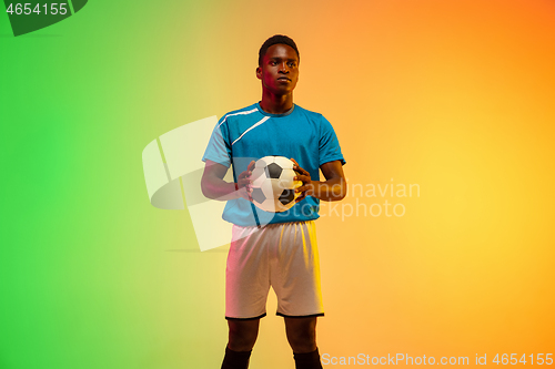 Image of Male soccer, football player training in action isolated on gradient studio background in neon light