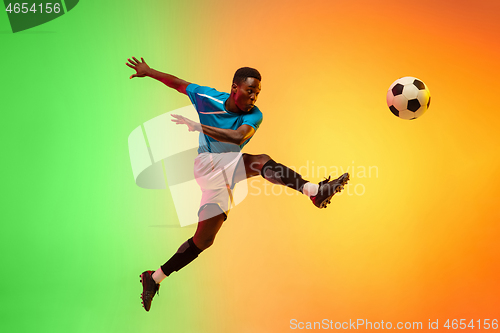 Image of Male soccer, football player training in action isolated on gradient studio background in neon light