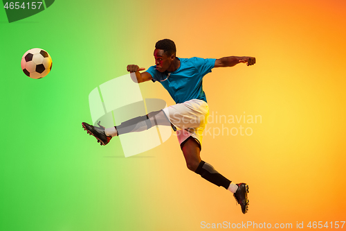 Image of Male soccer, football player training in action isolated on gradient studio background in neon light