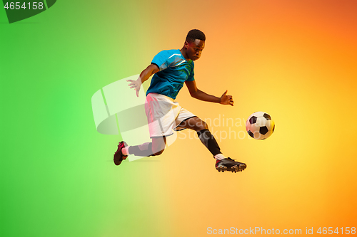 Image of Male soccer, football player training in action isolated on gradient studio background in neon light