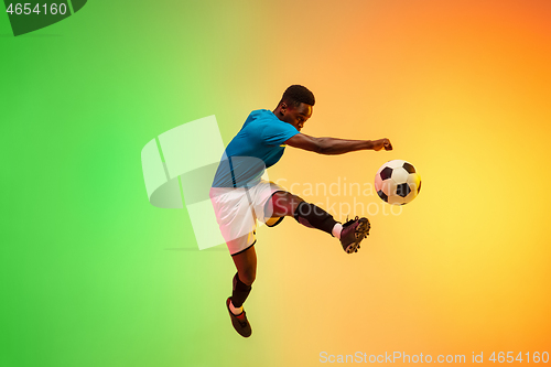 Image of Male soccer, football player training in action isolated on gradient studio background in neon light