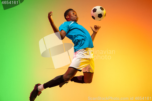 Image of Male soccer, football player training in action isolated on gradient studio background in neon light