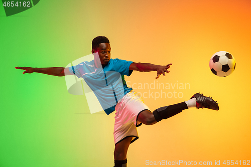 Image of Male soccer, football player training in action isolated on gradient studio background in neon light