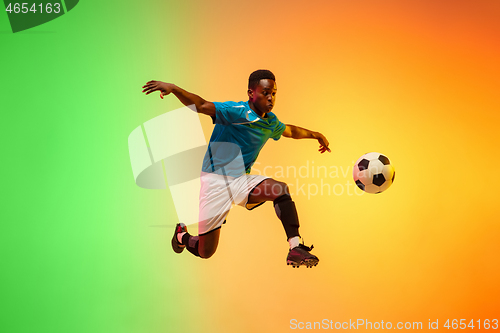 Image of Male soccer, football player training in action isolated on gradient studio background in neon light