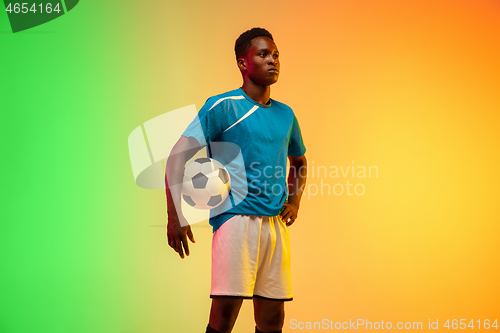 Image of Male soccer, football player training in action isolated on gradient studio background in neon light