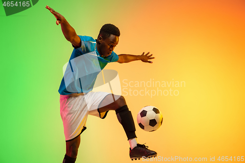 Image of Male soccer, football player training in action isolated on gradient studio background in neon light