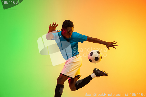 Image of Male soccer, football player training in action isolated on gradient studio background in neon light