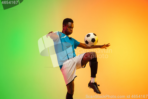 Image of Male soccer, football player training in action isolated on gradient studio background in neon light