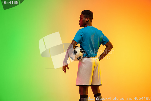 Image of Male soccer, football player training in action isolated on gradient studio background in neon light