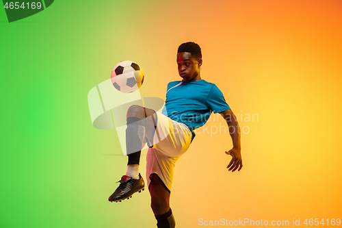 Image of Male soccer, football player training in action isolated on gradient studio background in neon light