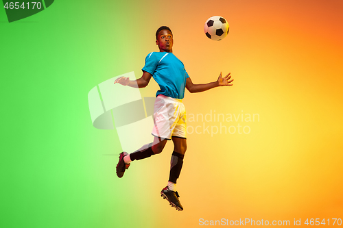 Image of Male soccer, football player training in action isolated on gradient studio background in neon light