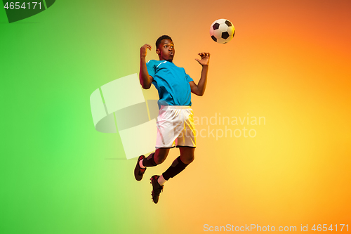 Image of Male soccer, football player training in action isolated on gradient studio background in neon light