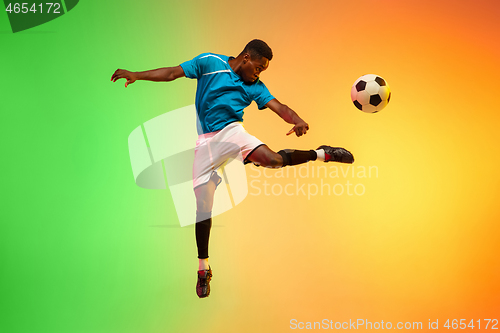 Image of Male soccer, football player training in action isolated on gradient studio background in neon light