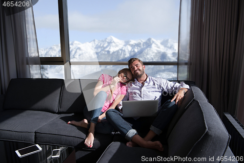 Image of couple relaxing at  home using laptop computers