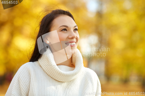 Image of portrait of happy young woman in autumn park