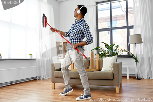 Image of man with broom cleaning and having fun at home