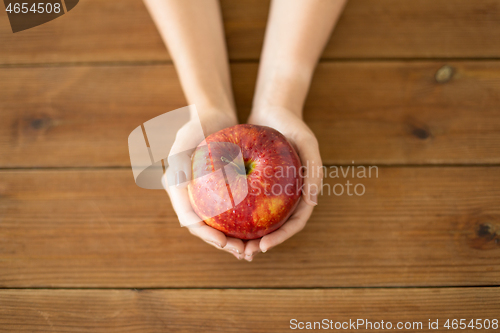 Image of close up of hands holding ripe red apple