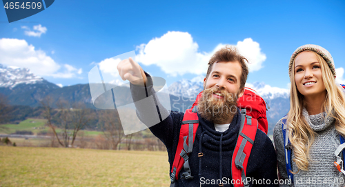 Image of smiling couple with backpacks hiking in autumn