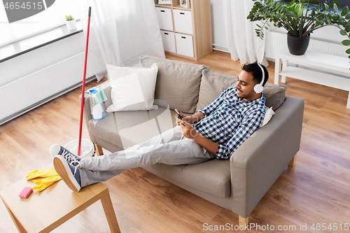 Image of indian man in headphones after cleaning home