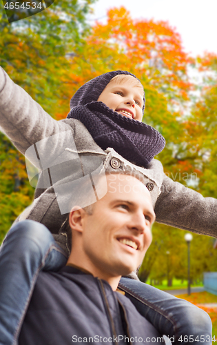 Image of happy family having fun in autumn park