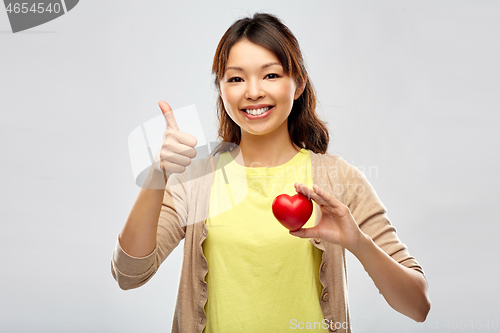 Image of happy asian woman with red heart showing thumbs up