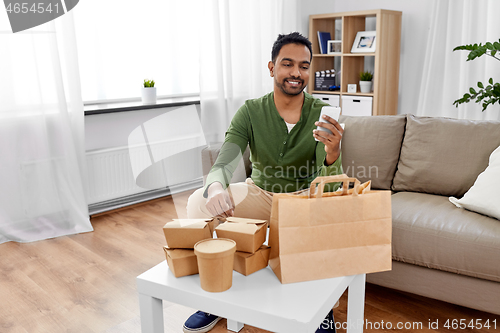 Image of indian man checking takeaway food order at home