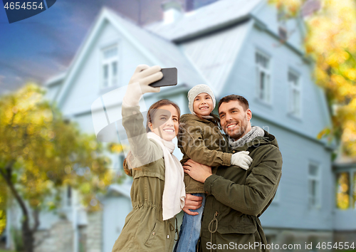 Image of family taking selfie by smartphone house in autumn