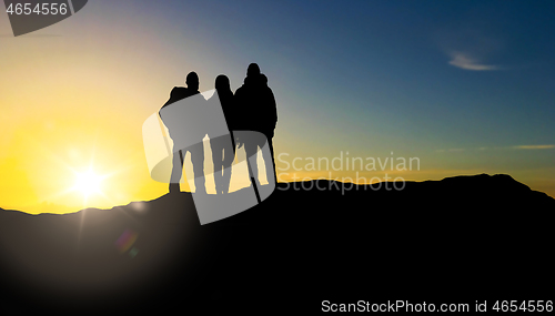 Image of group of travellers with backpacks over sunrise