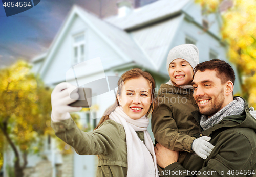 Image of family taking selfie over house in autumn