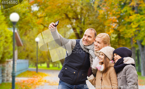 Image of happy family with camera in autumn park