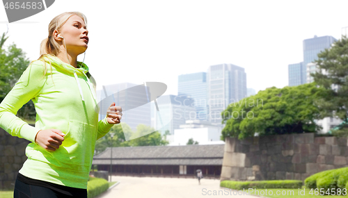 Image of woman with earphones running at city park