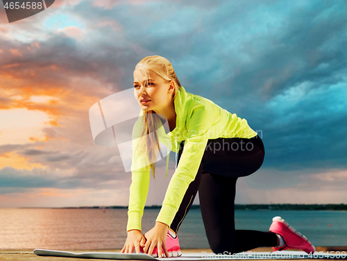 Image of woman stretching on exercise mat at seaside