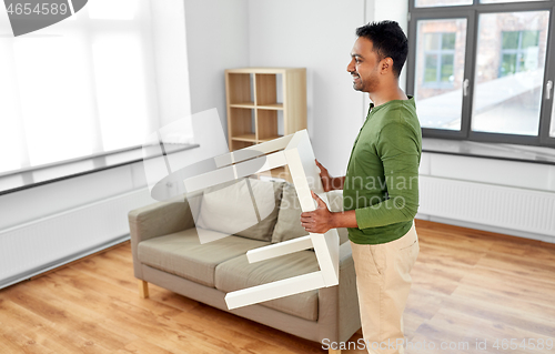 Image of happy indian man holding coffee table at home