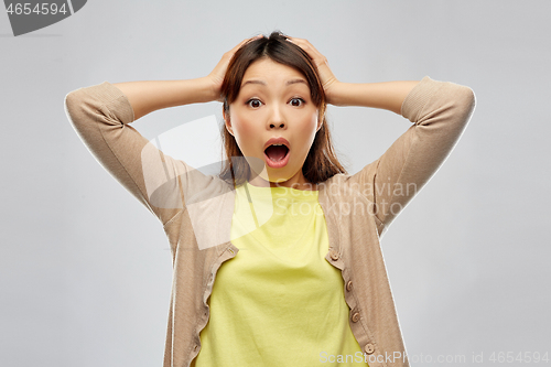 Image of shocked asian woman holding to her head