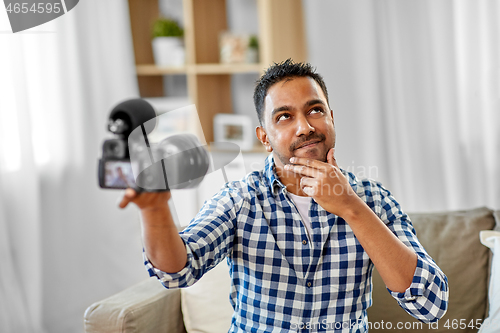 Image of male video blogger with camera blogging at home