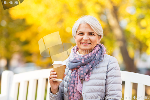 Image of senior woman drinking coffee in autumn park