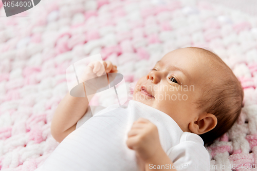 Image of sweet baby girl lying on knitted plush blanket