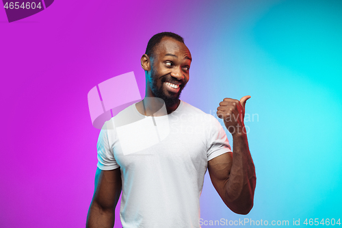 Image of African-american young man\'s portrait on gradient studio background in neon