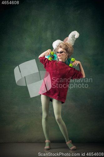 Image of Young woman as Marie Antoinette on dark background. Retro style, comparison of eras concept.